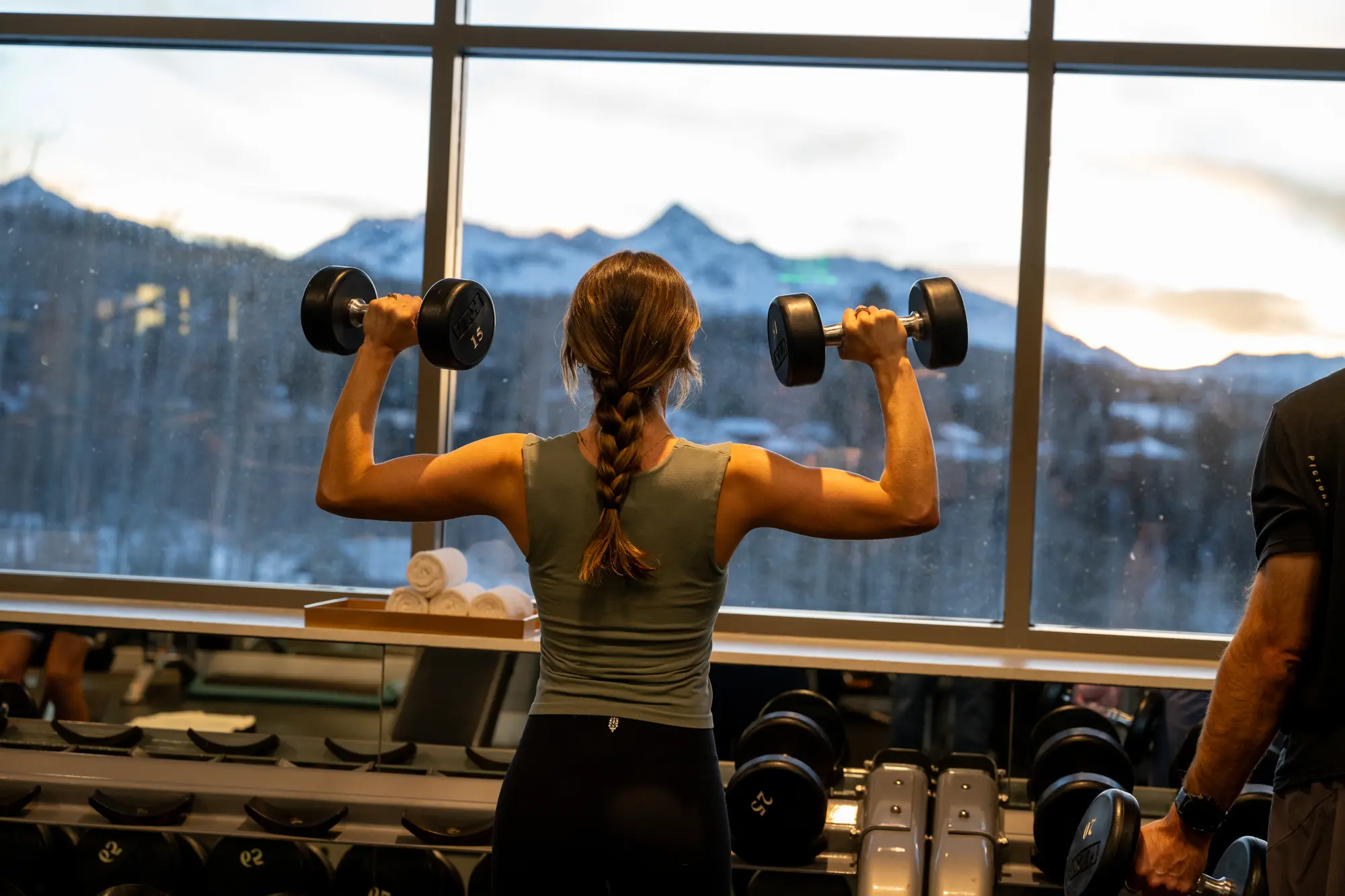 A guest strength training with dumbbells beside the mountain-facing windows